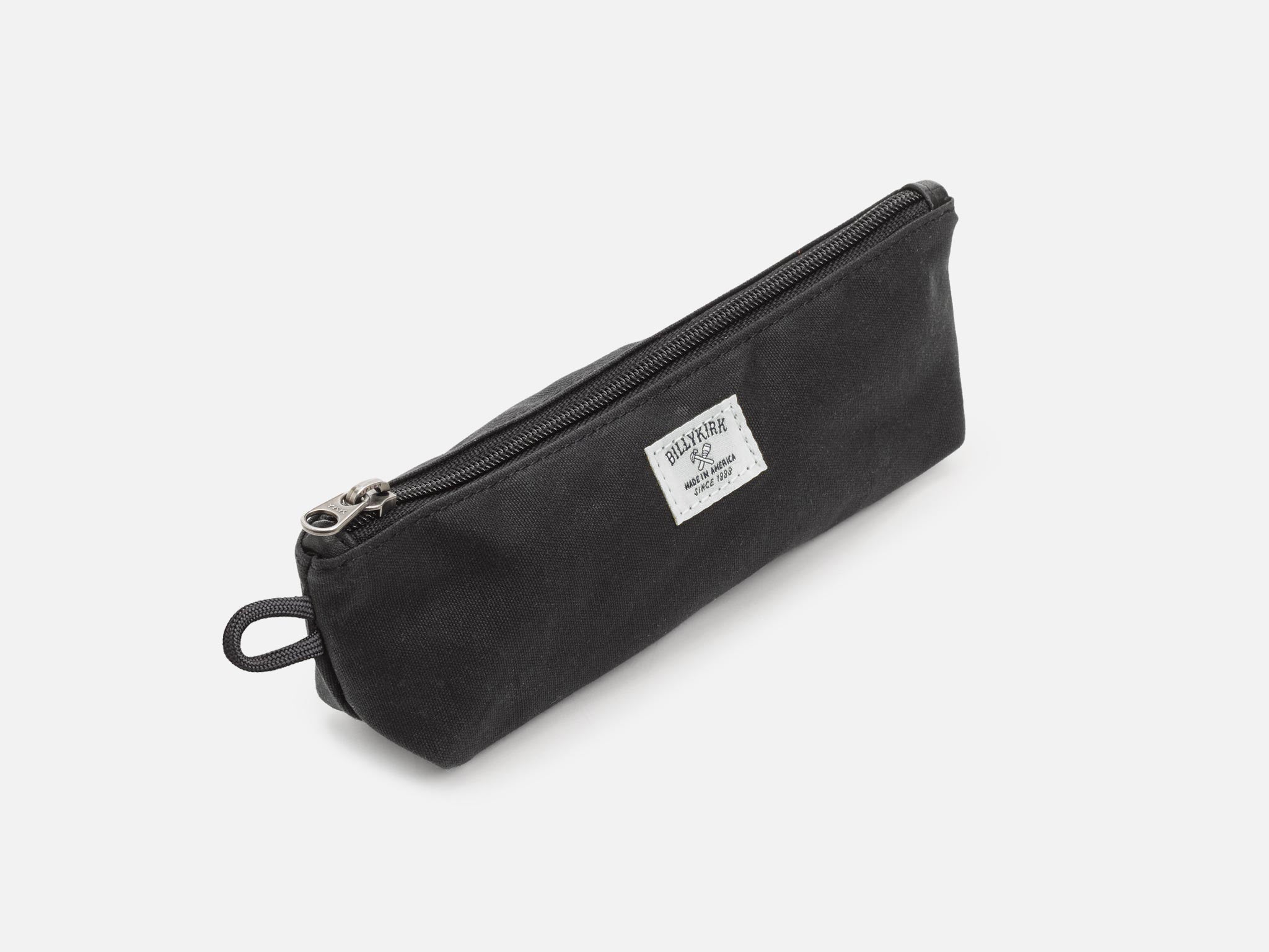 An black waxed canvas pouch with zipper closure on a neutral background. It features a cream woven tag that reads "Billykirk made in america since 1999".
