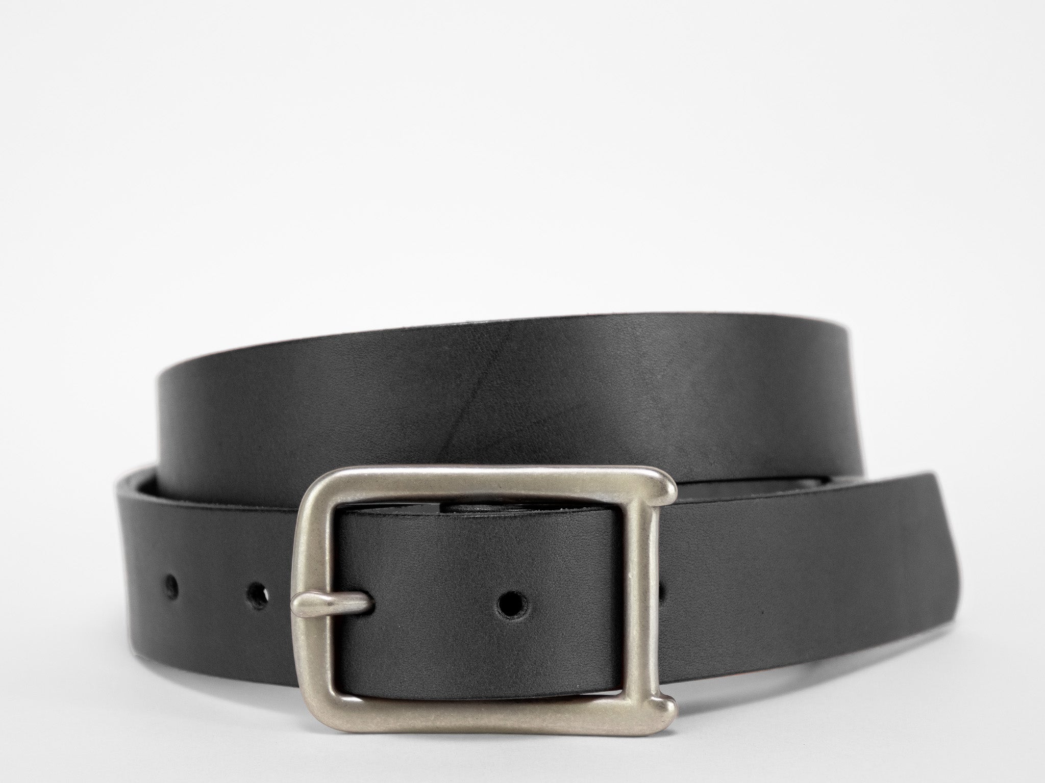A black leather belt with a silver rectangular buckle is coiled on a plain white background.