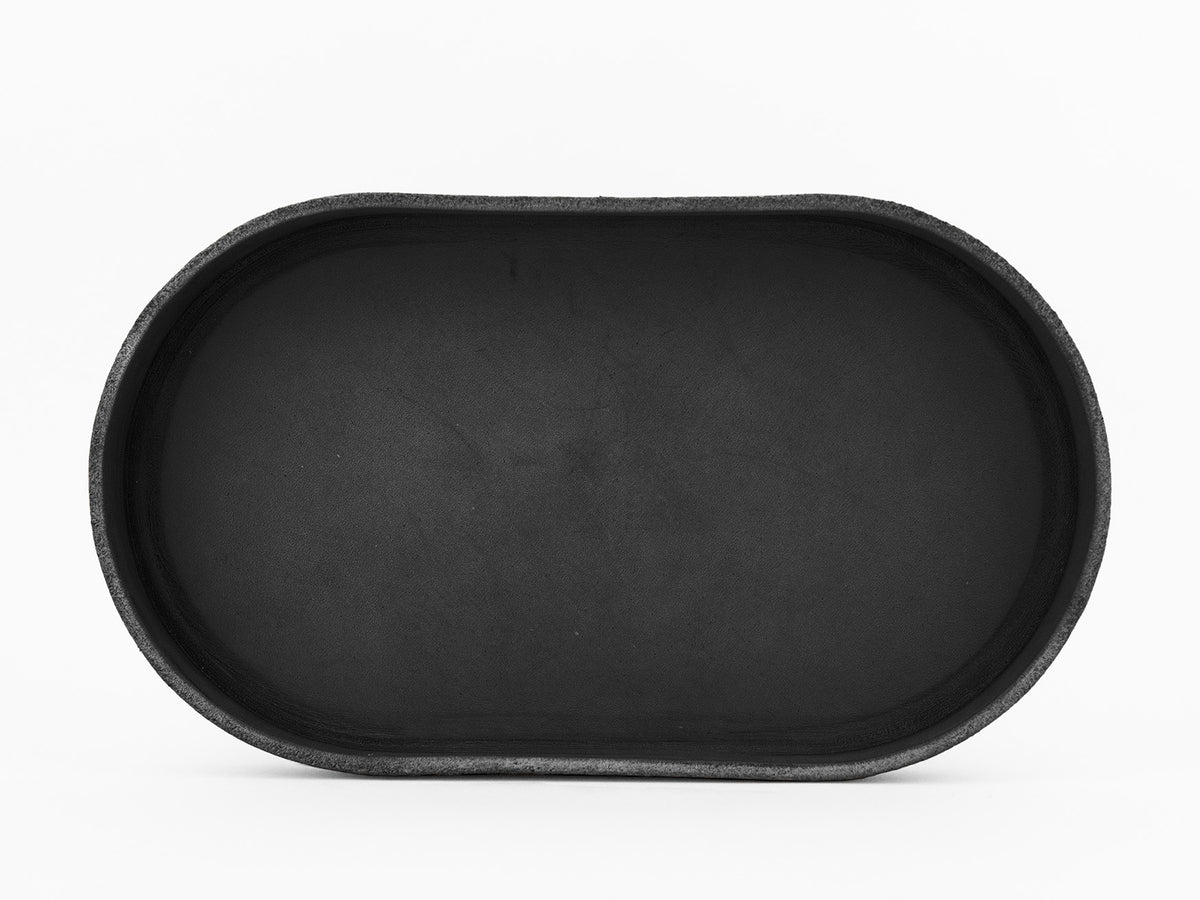 A black, oval-shaped tray with raised edges, photographed from above against a white background.