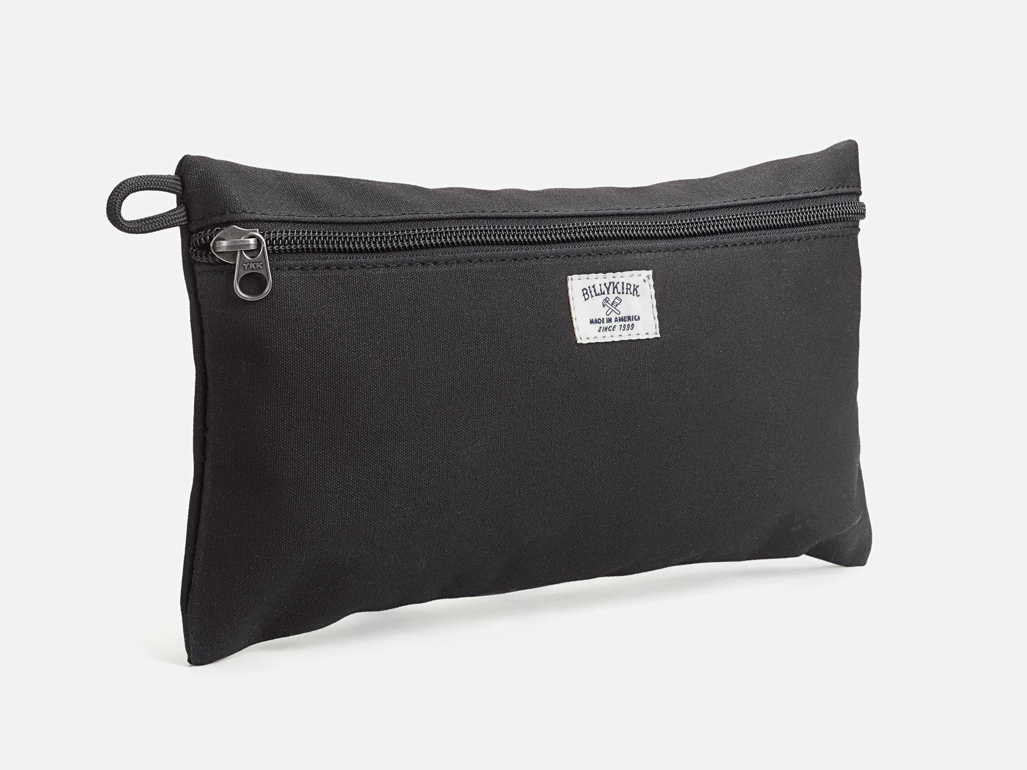 An black waxed canvas pouch with zipper closure on a neutral background. It features a cream woven tag that reads "Billykirk made in america since 1999".