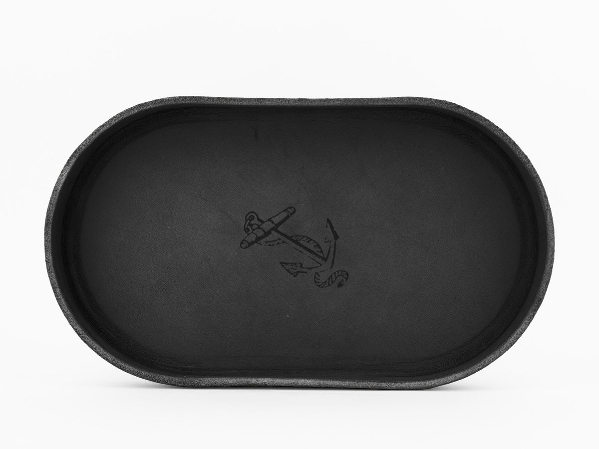 A black oval tray with a minimalist anchor and rope design engraved in the center, set against a white background.