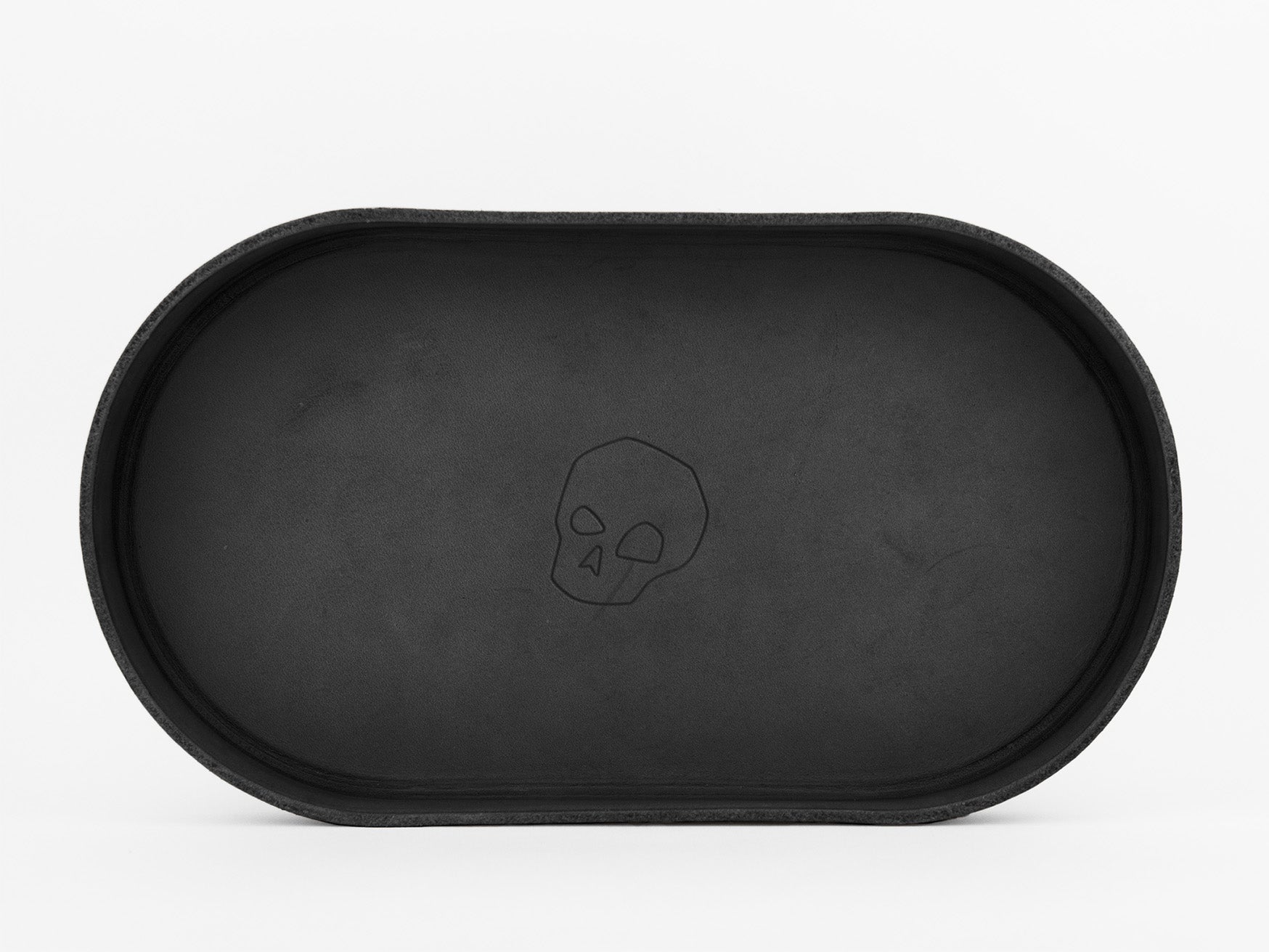 An oval-shaped black tray with a subtle, engraved skull design in the center, set against a plain white background.