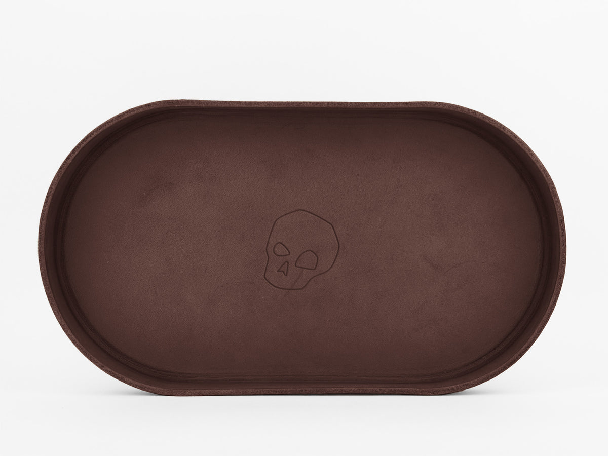 A brown oval tray with a simple, outlined skull design in the center, set against a plain white background.