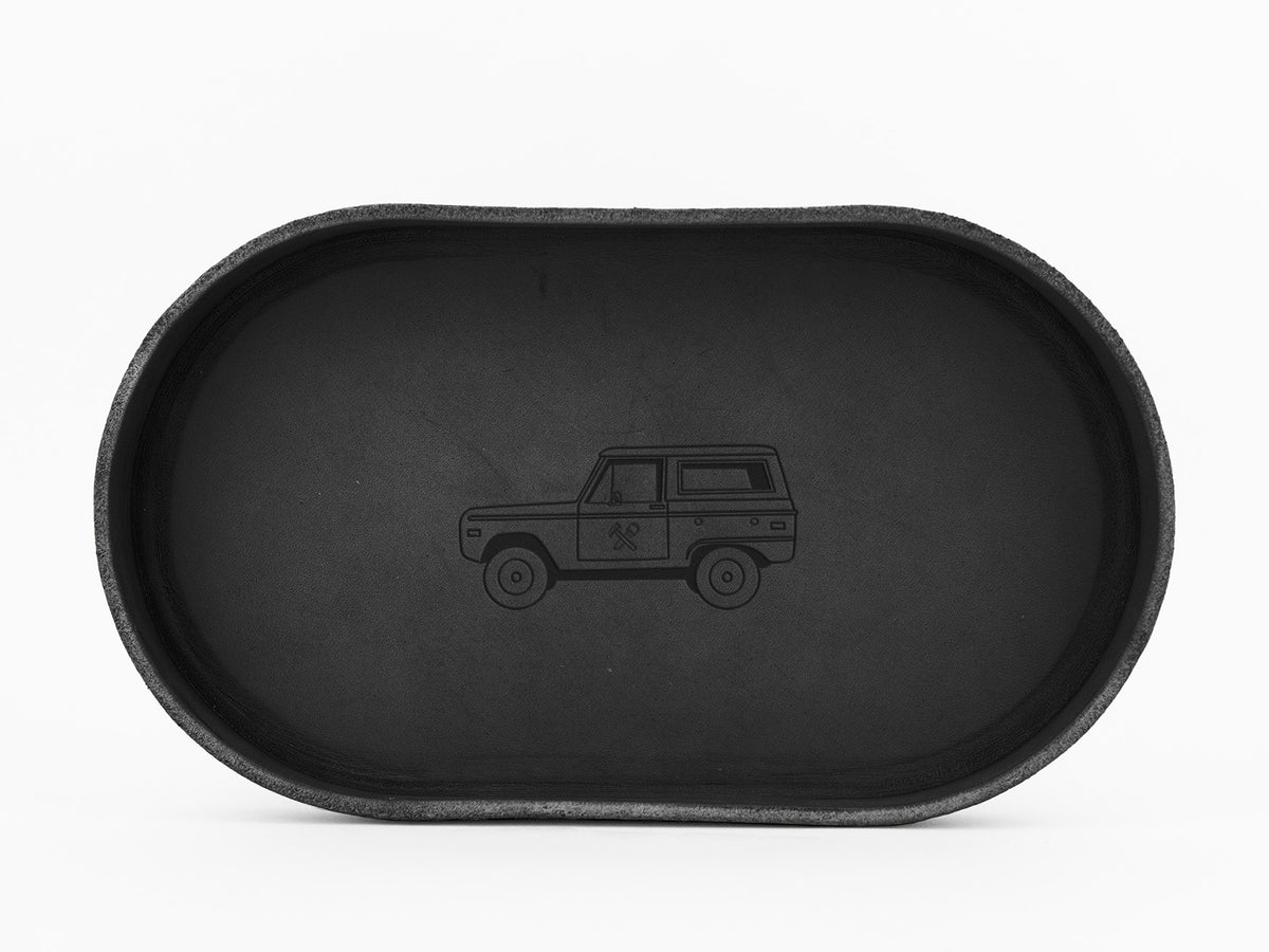 A black, oval-shaped tray with a simple, engraved outline of an SUV or off-road vehicle in the center, displayed against a white background.
