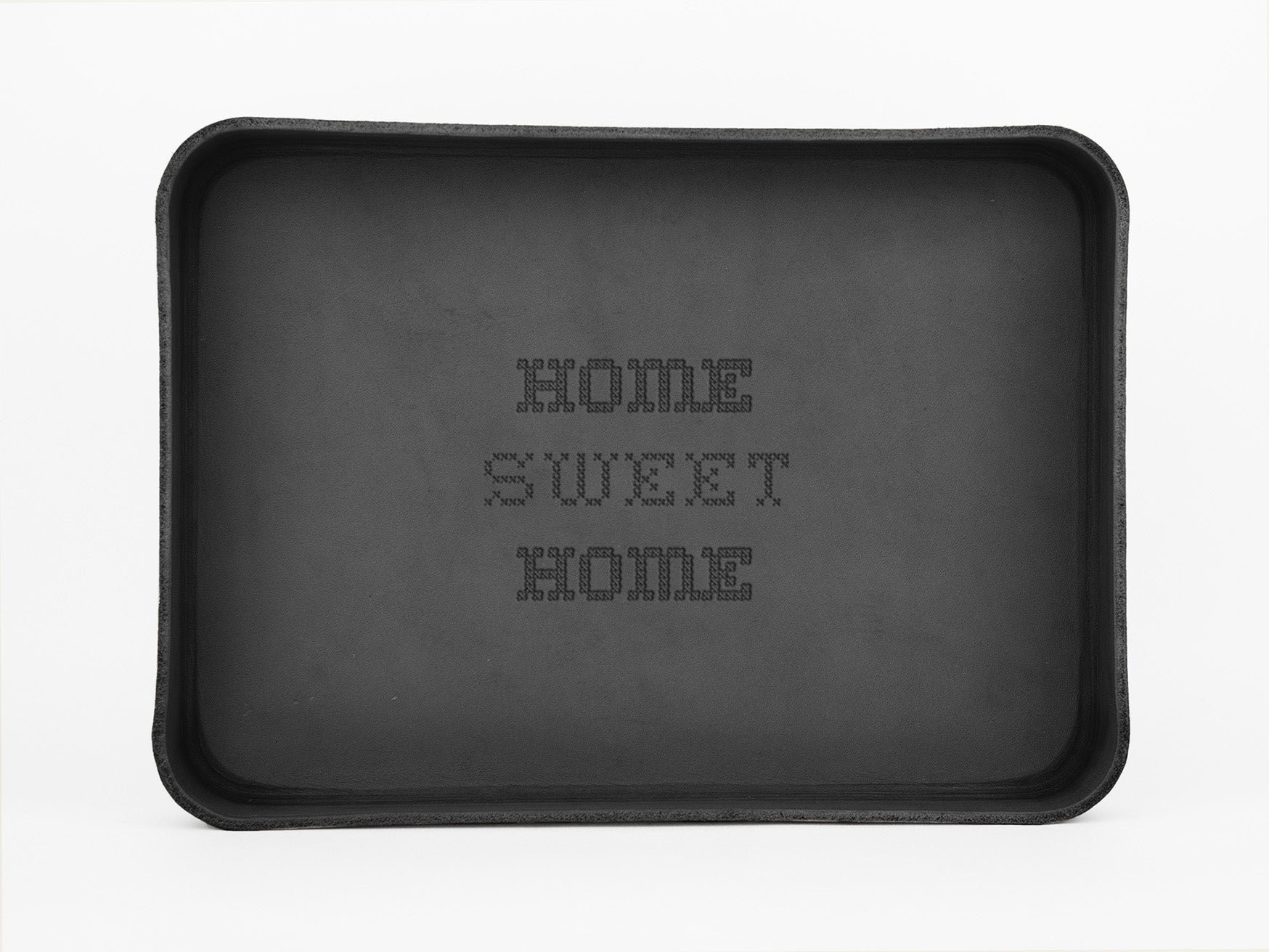 A black rectangular tray with the words HOME SWEET HOME spelled out in a dotted pixel-like font in the center. The background is plain white.