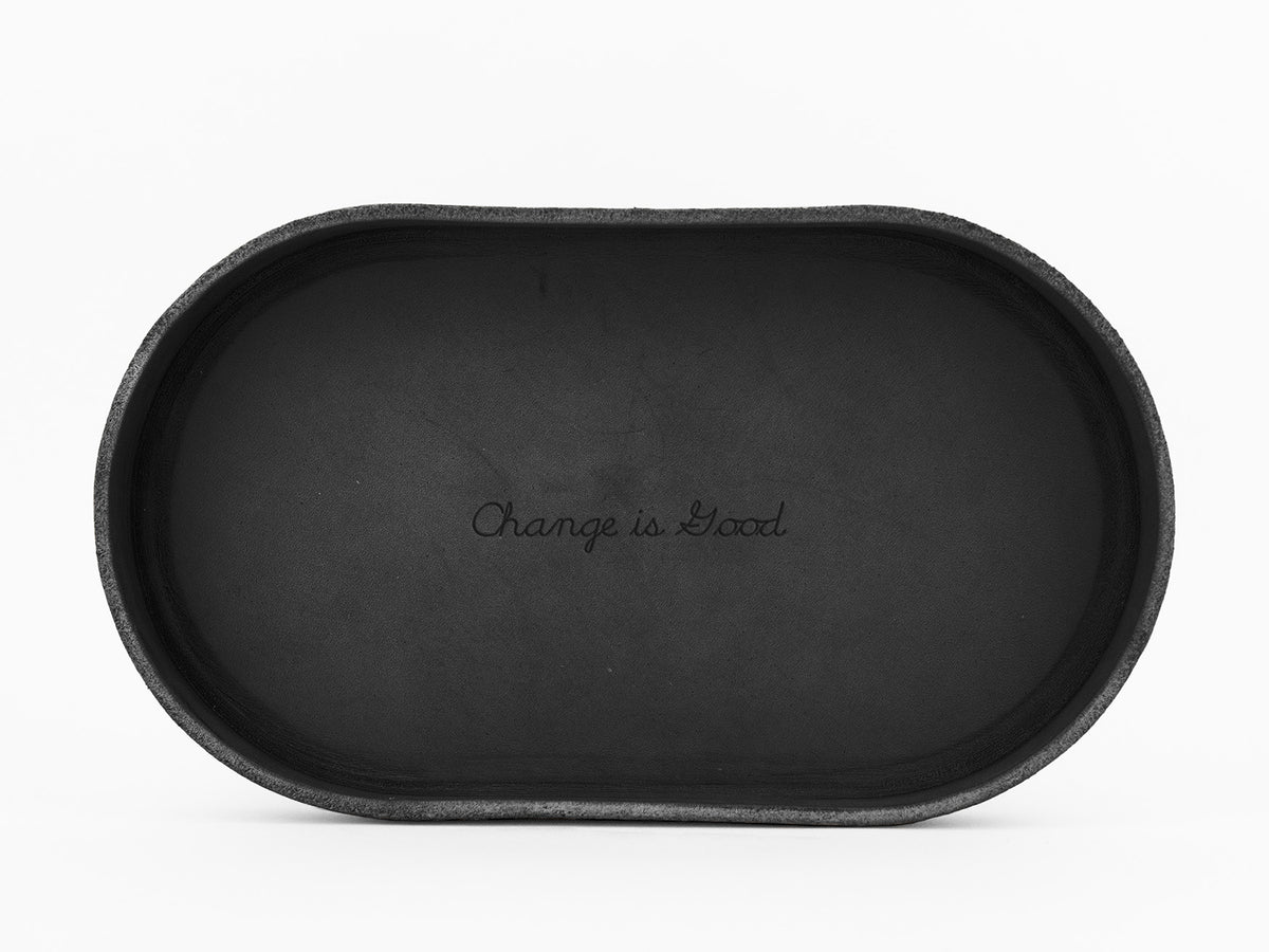 A black, oval-shaped tray with the phrase Change is Good engraved in script font at the center, set against a white background.