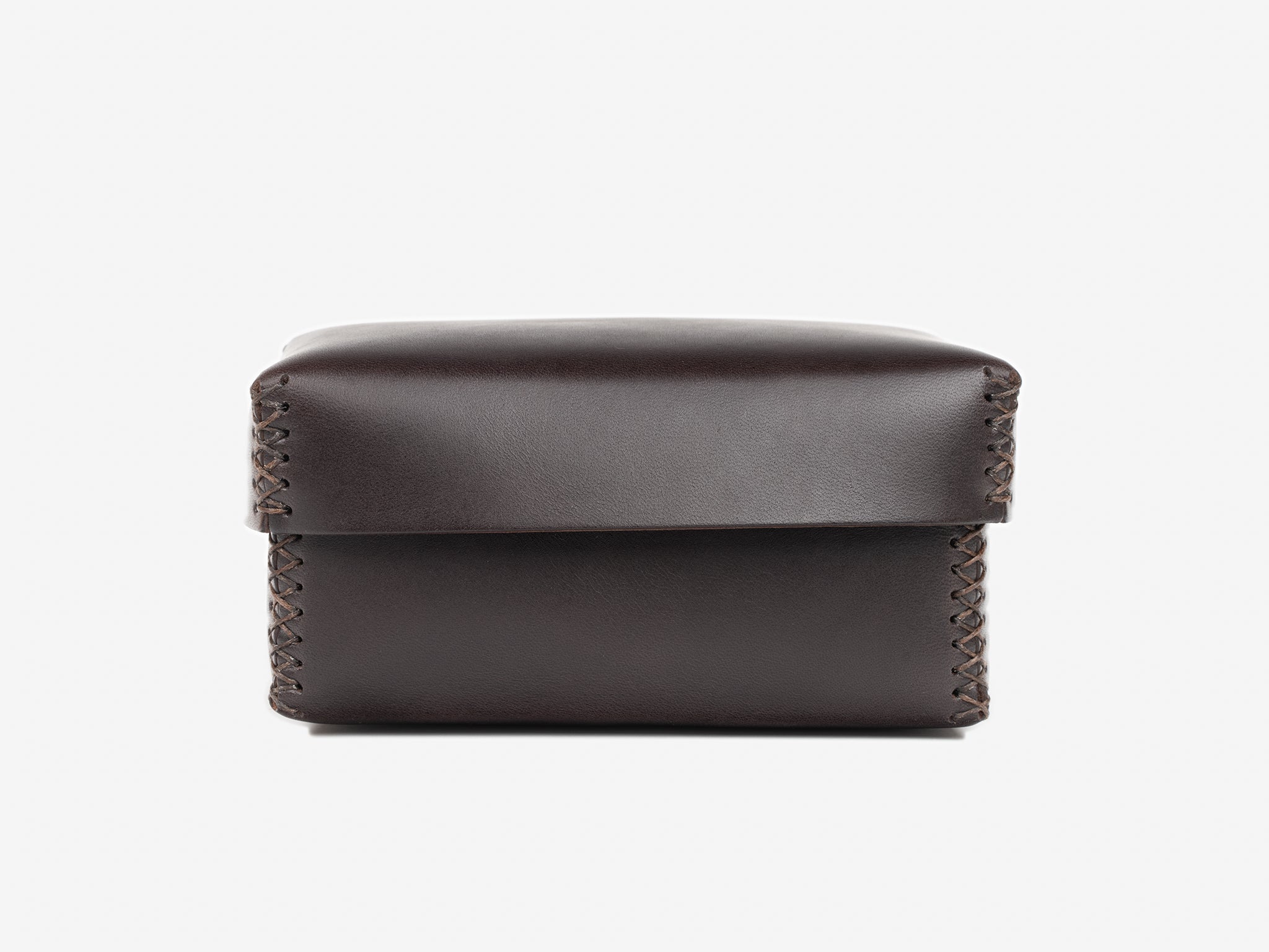 A small, dark brown leather box with visible stitching along the sides, photographed against a plain white background.