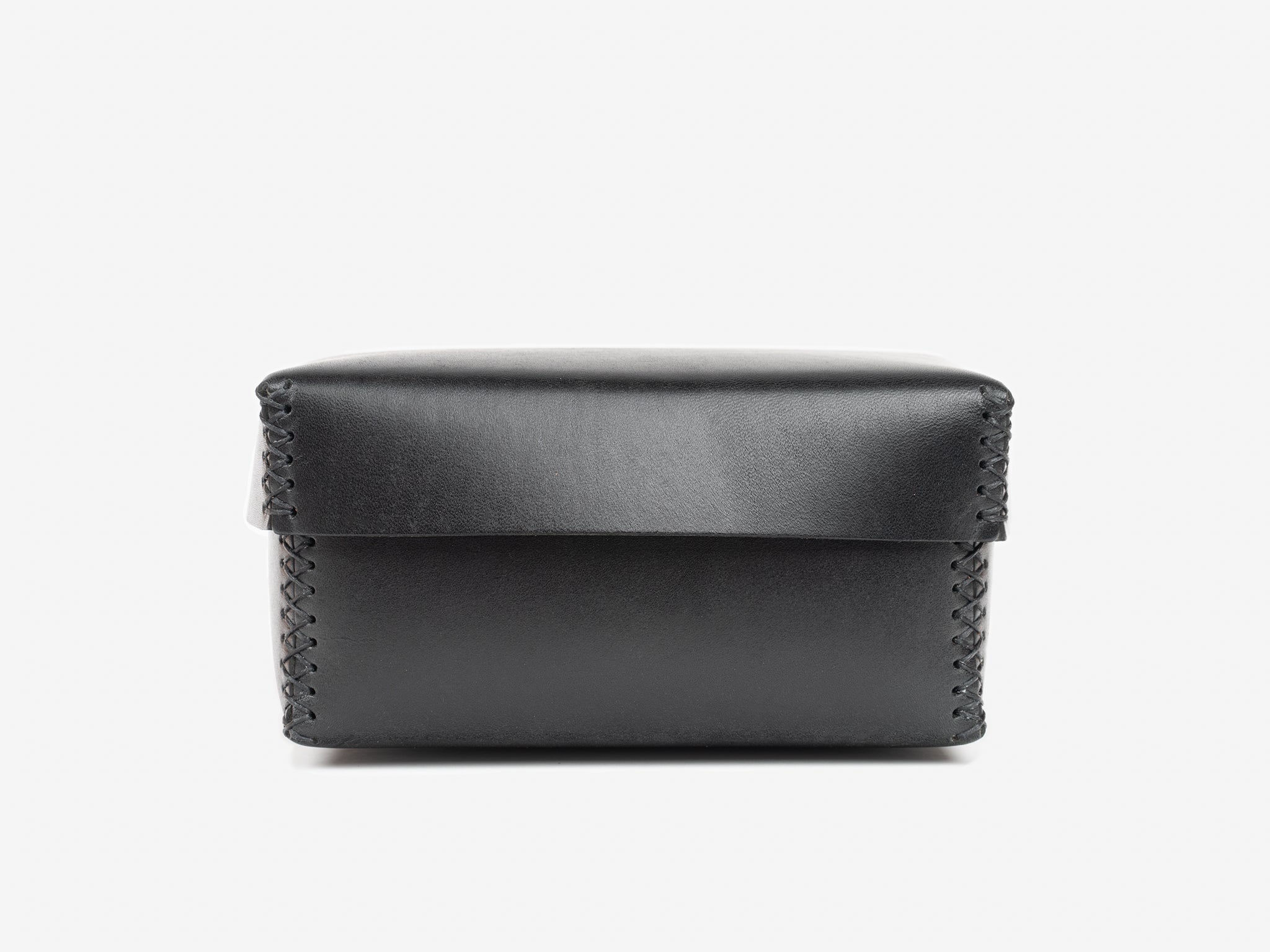 A black rectangular leather box with a flap lid and visible stitching along the edges, set against a plain white background.