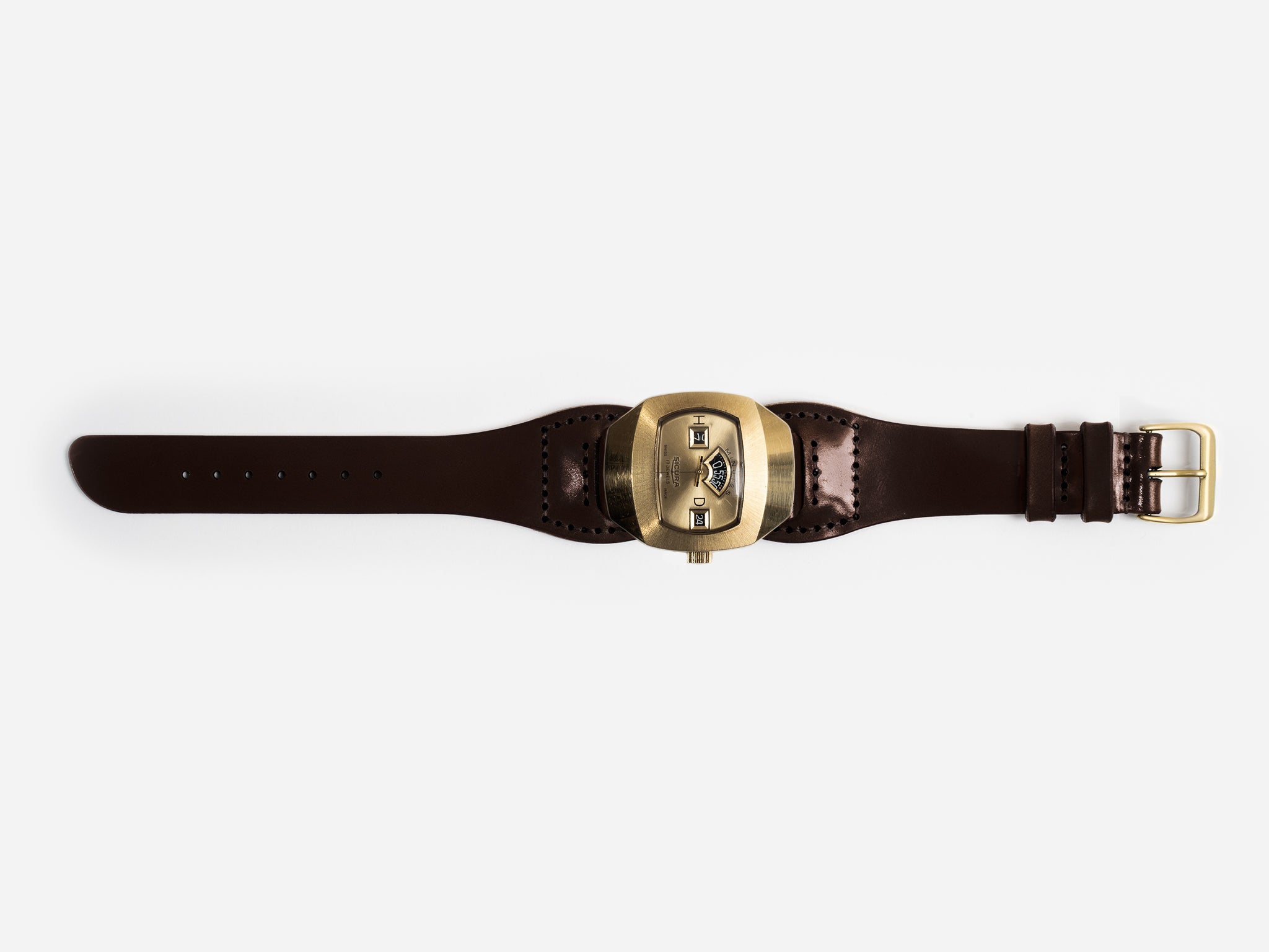 An hourglass-shaped dark brown cordovan leather strap and a large, brass-toned watch face featuring three small rectangular windows displaying the time digitally.