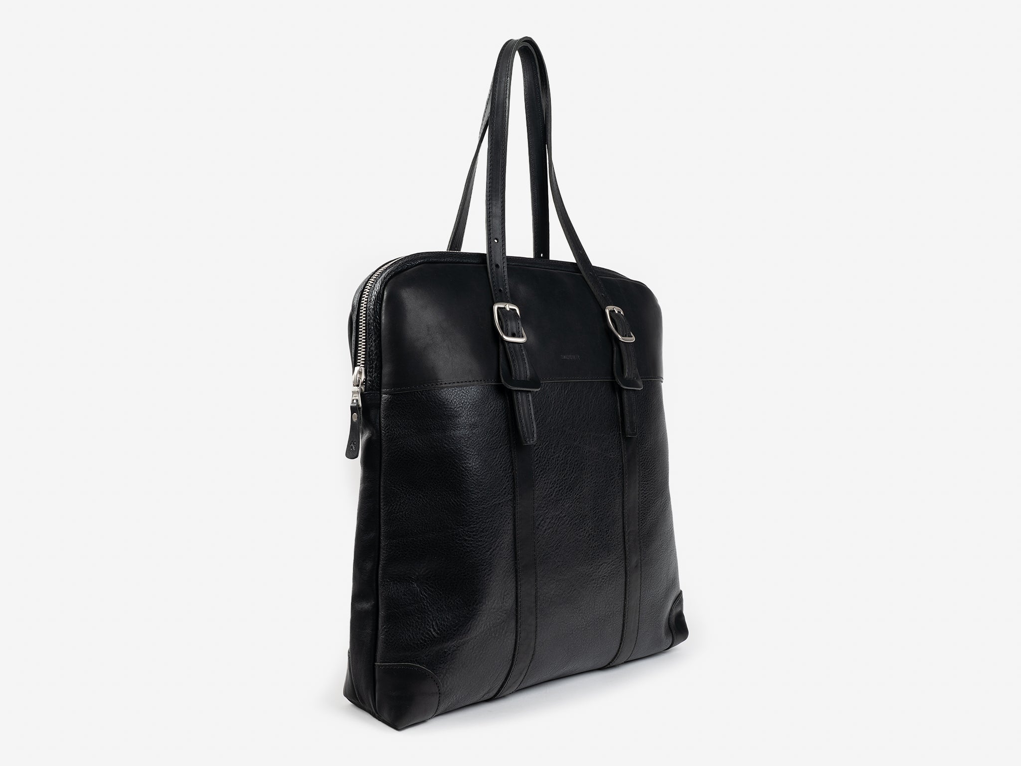 A black leather tote bag with two shoulder straps, a zipper closure, and metal buckle accents, shown standing upright on a plain white background.