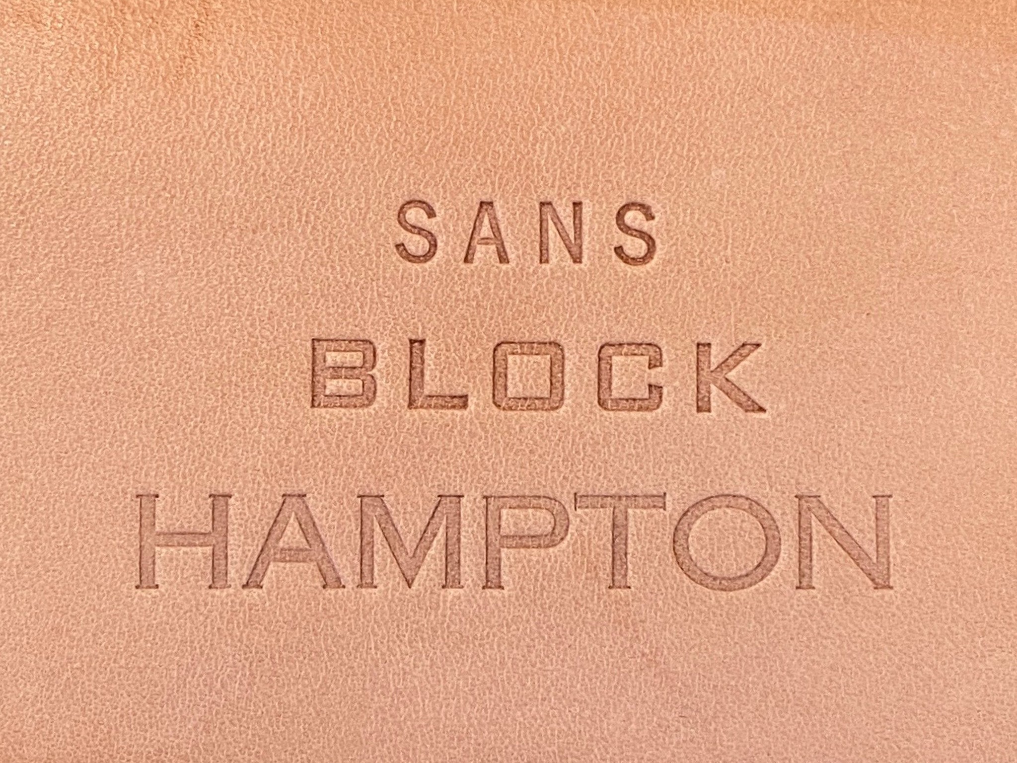 Embossed text on light brown leather reads: SANS in small letters, BLOCK in medium-sized block letters, and HAMPTON in large capital letters.