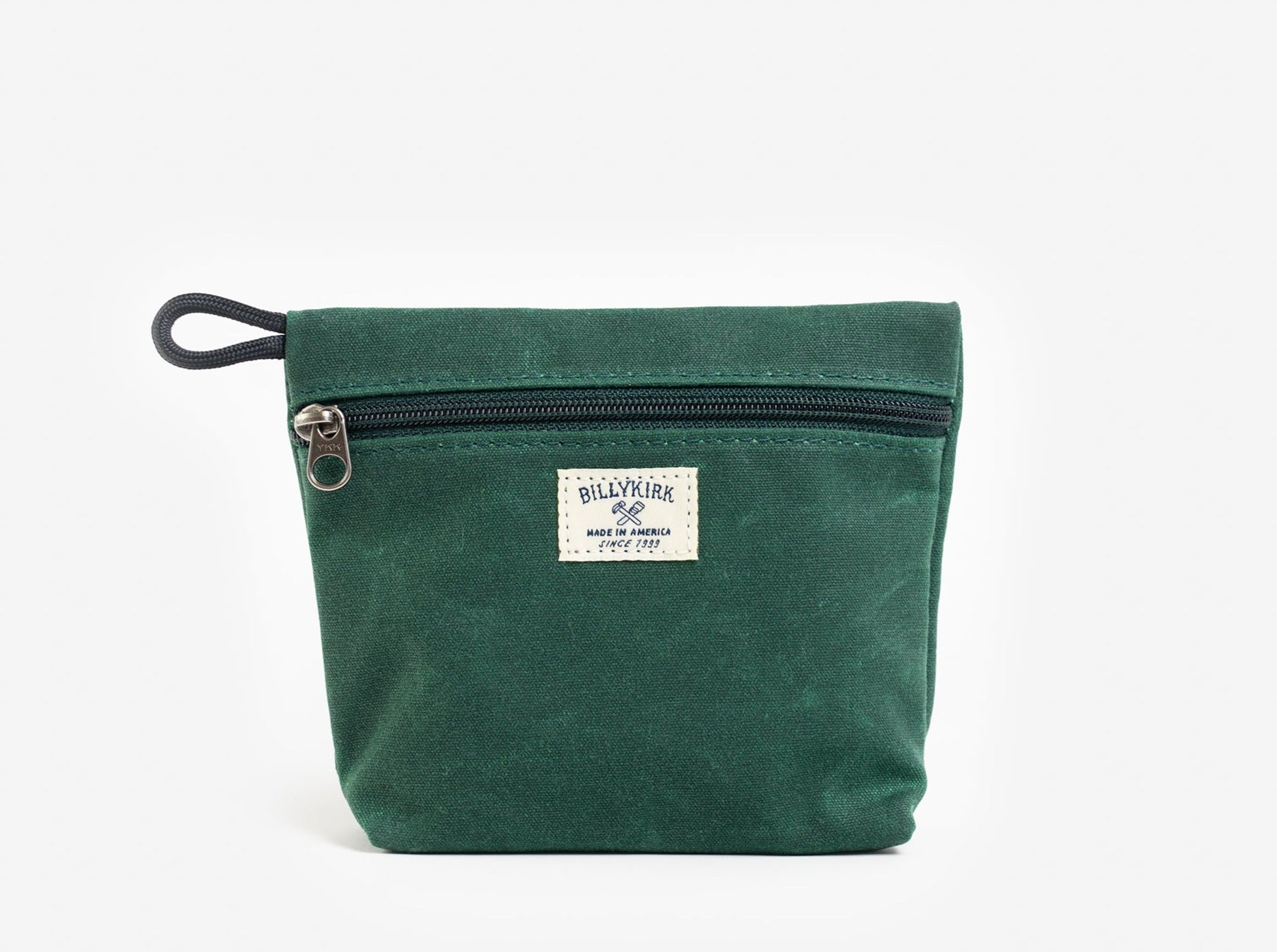 A green waxed canvas pouch with zipper closure on a neutral background. It features a cream woven tag that reads "Billykirk made in america since 1999".