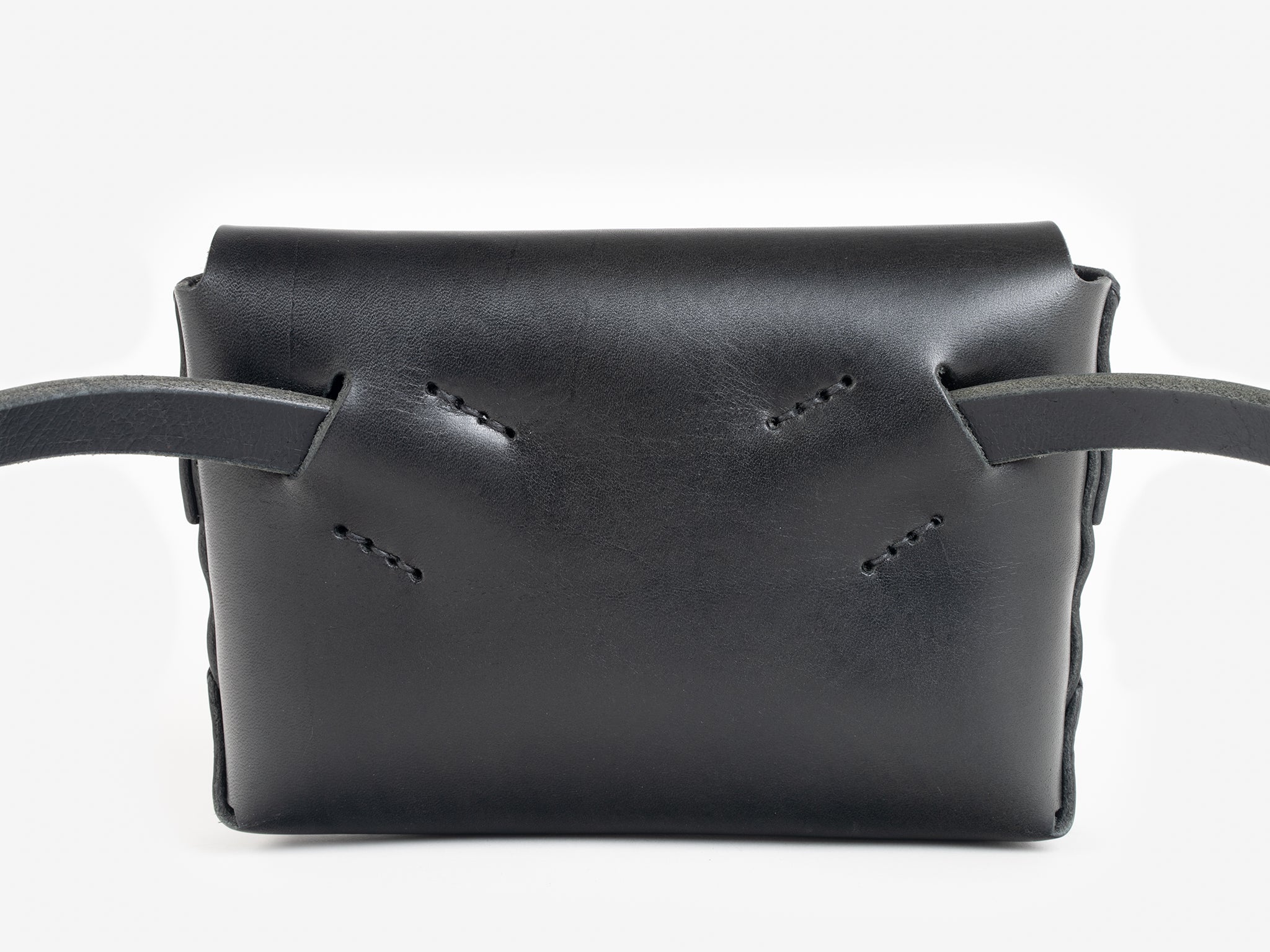 Back view of a black leather belt crossbody bag with a smooth finish, featuring  hand-stitching details, displayed against a white background.