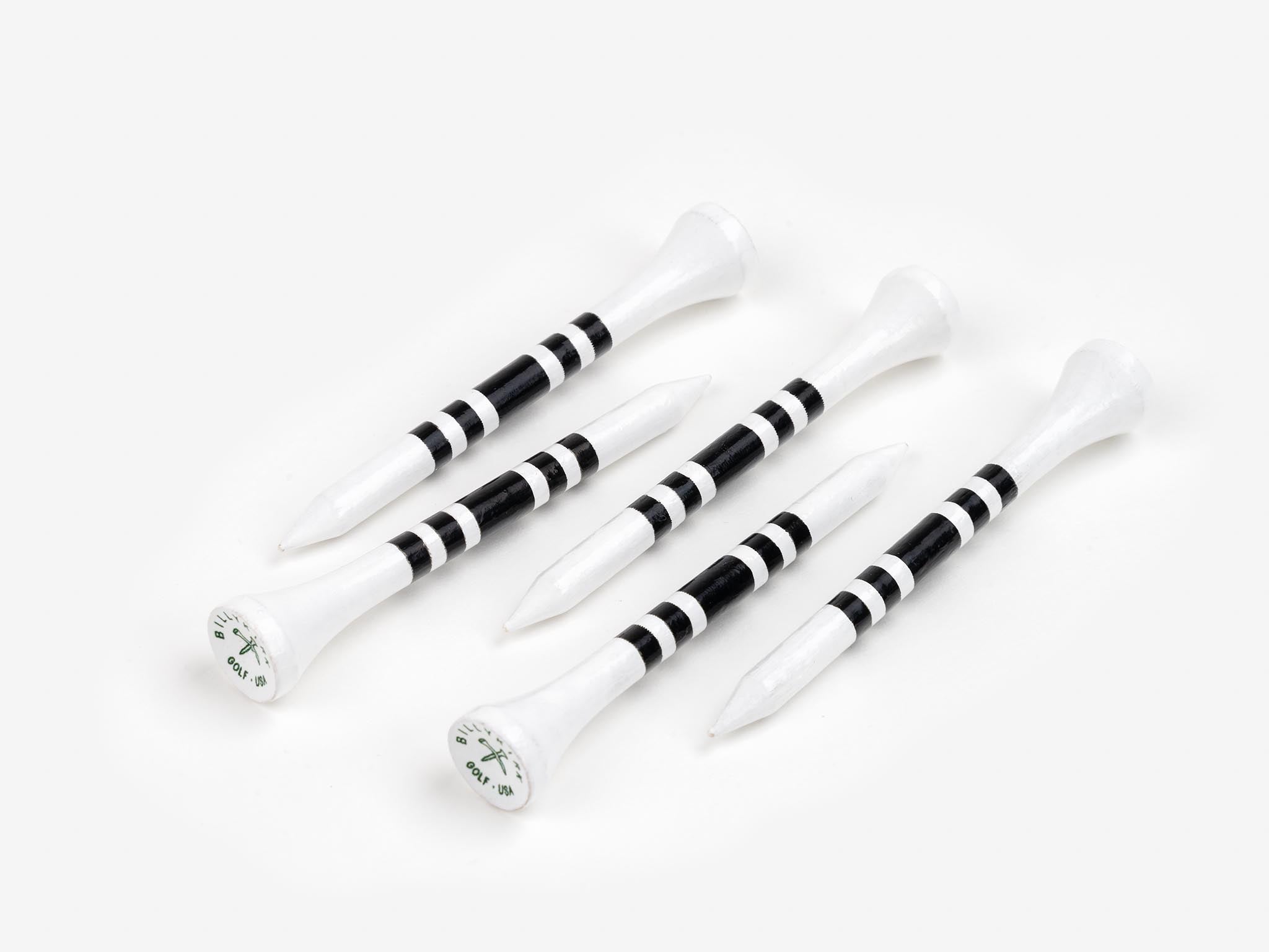 Five white golf tees with black stripes are arranged diagonally on a white background. The tops of the tees have a small logo or text printed on them.
