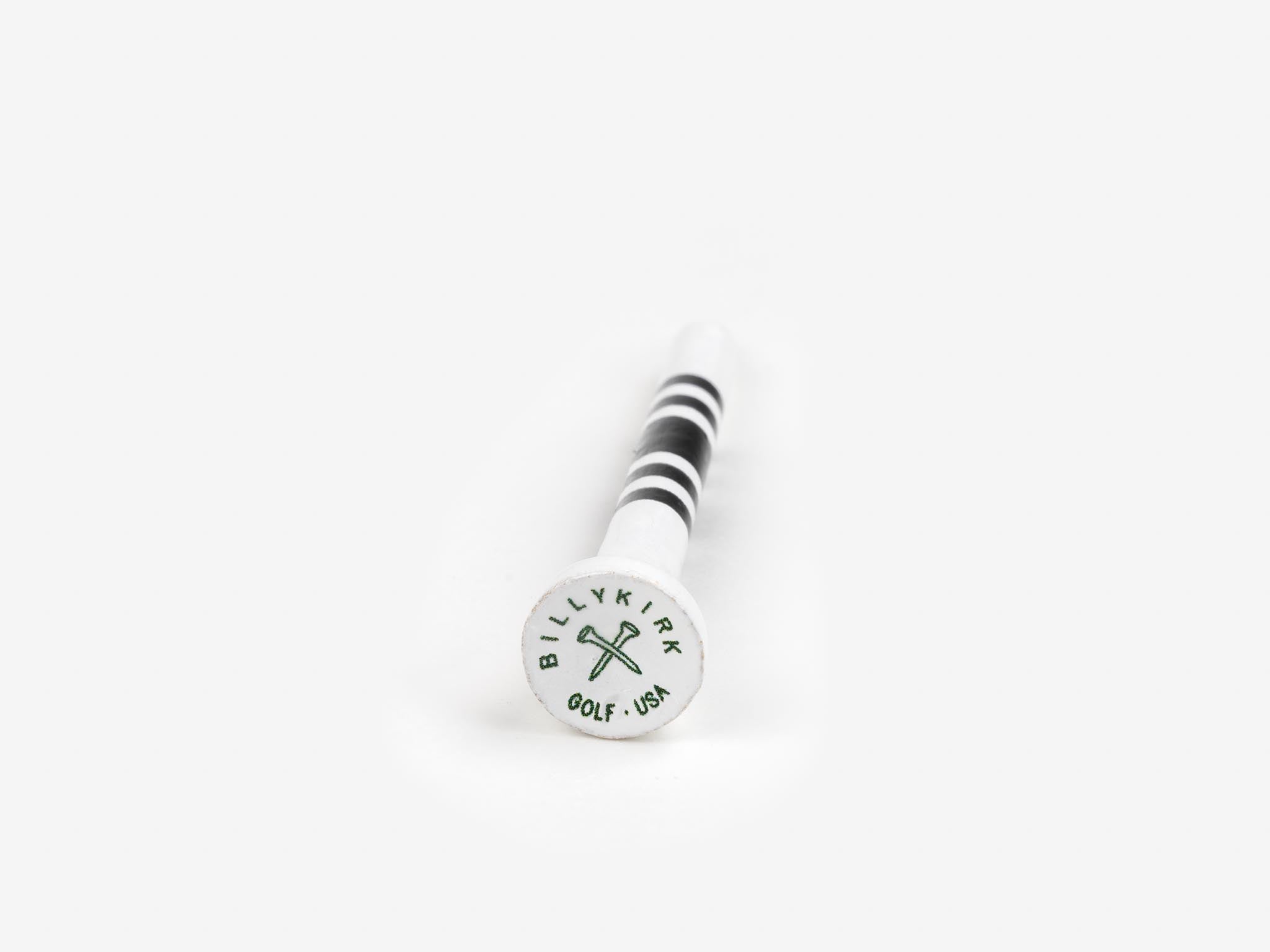 A white golf tee with black stripes lies on a white surface. The base of the tee displays the text BILLYKIRK GOLF USA and a crossed golf club logo in green.